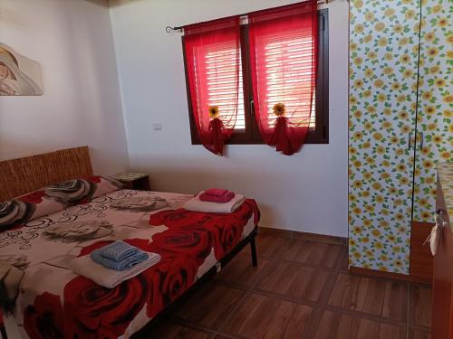 1 dormitorio con 1 cama y 2 ventanas con cortinas rojas en Casa Nonna Pina en Fanusa