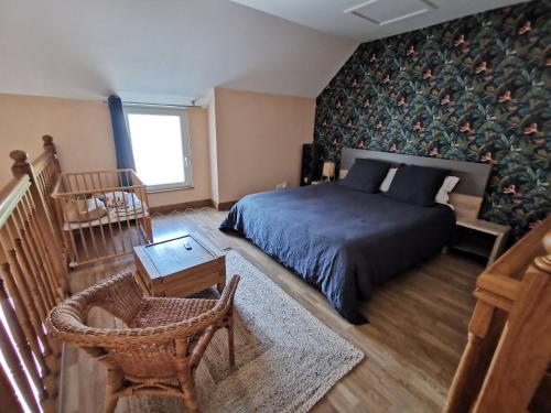 a bedroom with a bed and a table and a chair at Gîte Le Petit Bacchus in Sainte-Croix-Hague
