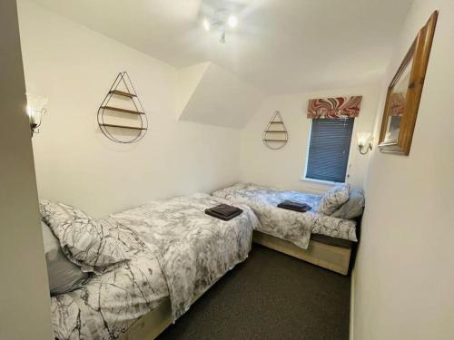 2 Einzelbetten in einem Schlafzimmer mit Fenster in der Unterkunft Orchid Cotswold Stone house in Swindon