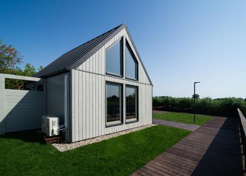 a small white building with windows on a lawn at Folwark Żuławski in Elblag