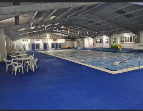 a large swimming pool with tables and chairs in a building at East Coast Chalets 58 at California Sands Dog Friendly in Great Yarmouth