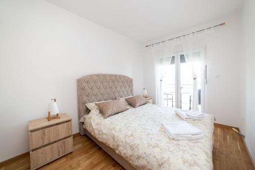 a white bedroom with a large bed and a window at Pinnacle MNE in Žabljak