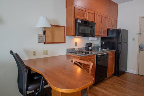 a kitchen with a wooden table and a black refrigerator at Candlewood Suites New Iberia by IHG in New Iberia