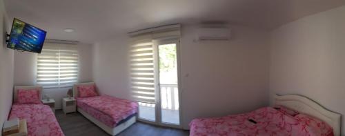 a room with pink beds and a flat screen tv at Apartmani Hani in Trebinje