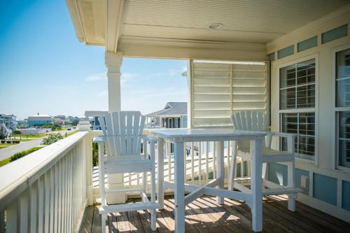 two chairs and a table on the porch of a house at The Anchor Holds by Oak Island Accommodations in Oak Island