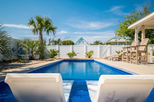 a swimming pool with chairs and a white fence at The Anchor Holds by Oak Island Accommodations in Oak Island