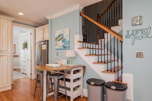 a kitchen with a table and a staircase with stools at The Anchor Holds by Oak Island Accommodations in Oak Island