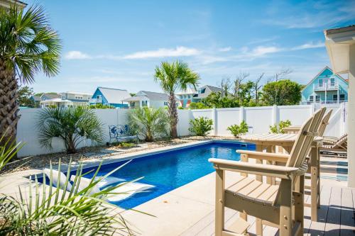 a swimming pool with a table and chairs next to a fence at The Anchor Holds by Oak Island Accommodations in Oak Island