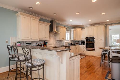 a kitchen with white cabinets and a island with bar stools at The Anchor Holds by Oak Island Accommodations in Oak Island