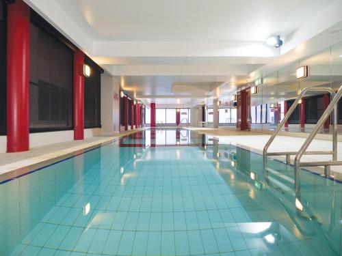 a swimming pool with blue tile floors and red columns at Oaks Adelaide Horizons Suites in Adelaide