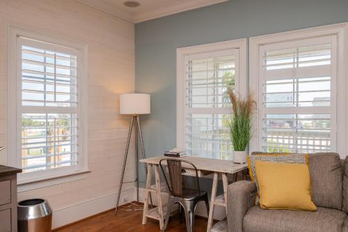 a living room with windows and a table and a couch at The Anchor Holds by Oak Island Accommodations in Oak Island