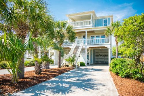 a house with palm trees in front of it at The Anchor Holds by Oak Island Accommodations in Oak Island