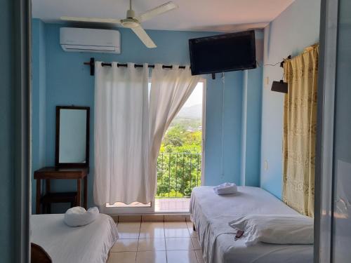 a bedroom with two beds and a large window at Casa La Paz 1 in Puerto Escondido