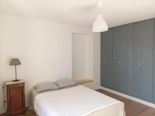 a bedroom with a white bed and a blue cabinet at Plein centre, T3, 2ch, balcon et vue in Mèze