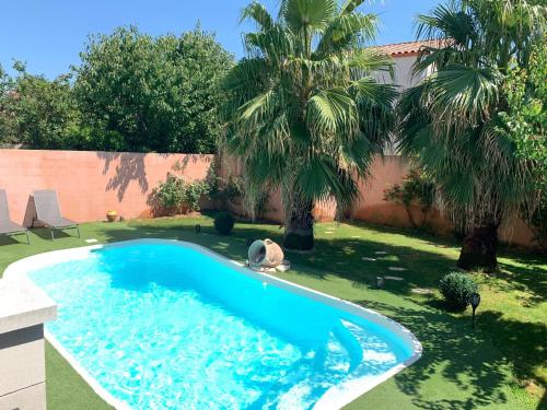 einen Pool in einem Garten mit zwei Palmen in der Unterkunft Villa provençale climatisée avec piscine privée in Saint-Gilles