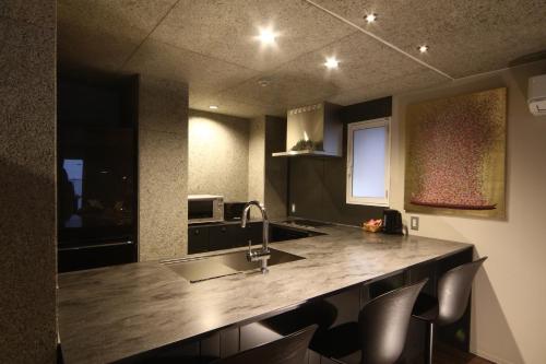 a kitchen with a counter with a sink and chairs at Private house Kuranoya Sapporo in Sapporo