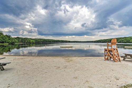a beach with two chairs and a bench and a lake at Near Skiing and Hiking Gouldsboro Home with Hot Tub in Gouldsboro