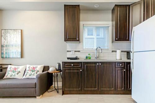 a kitchen with a couch and a white refrigerator at Rare Find Exquisitely New Quiet & Safe Skytrain Home in Vancouver