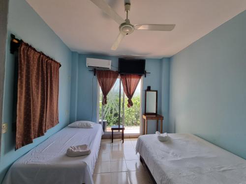 two beds sitting in a room with a window at Casa La Paz 2 in Puerto Escondido