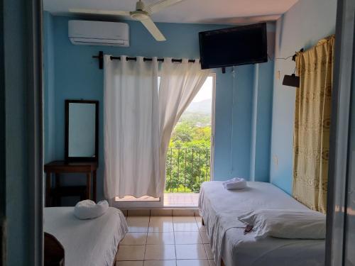 a bedroom with two beds and a large window at Casa La Paz 2 in Puerto Escondido