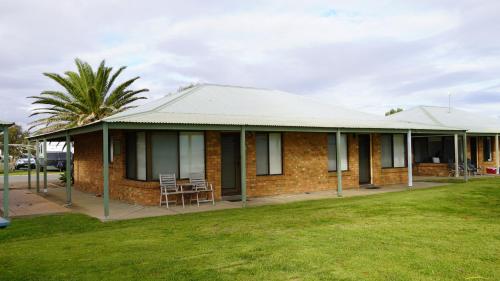 a brick house with a porch and a palm tree at Wallaroo Holiday Park in Wallaroo