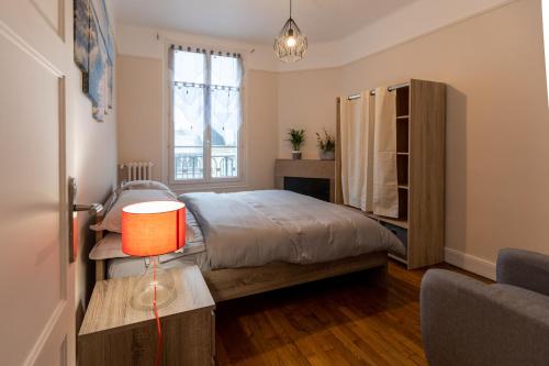 une chambre avec un lit et une table avec une lampe dans l'établissement Le Mans Appartement Gare TGV et proche centre, au Mans