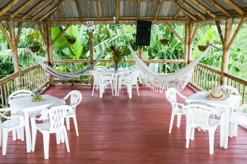 a porch with white tables and chairs and hammocks at Chalet Villa Alejandra Del Pilar in Quimbaya
