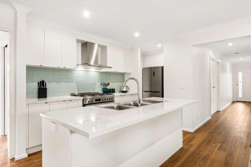 a white kitchen with a sink and a stove at Bronzewing Haven in Cowes