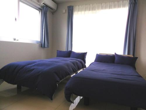 two beds in a room with a window at 与那覇コテージ　Yonaha Cottage in Yonaha