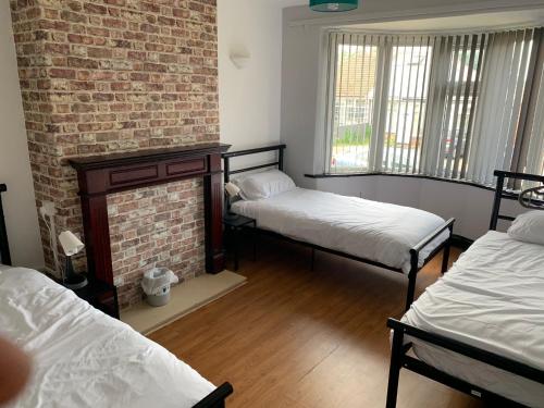 a room with two beds and a brick wall at Ovington Grove 1 free parking fully equipped kitchen 3 bedrooms Netflix in Newcastle upon Tyne