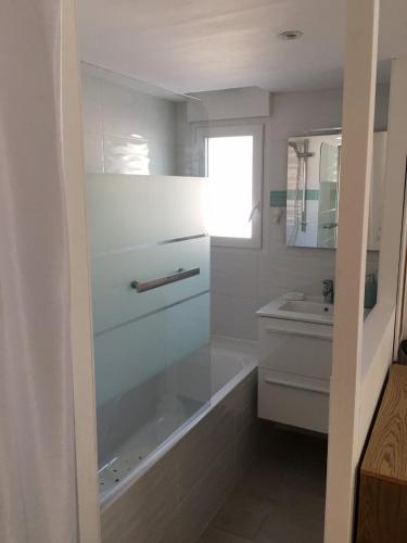 une salle de bain avec une baignoire et un lavabo dans l'établissement L'Augustémile au bord de l'eau, à La Tranche-sur-Mer