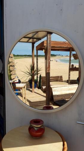 un miroir sur un mur avec une table et une plage dans l'établissement L'Augustémile au bord de l'eau, à La Tranche-sur-Mer