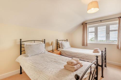 two twin beds in a bedroom with a window at Wood Cottage in Tenbury