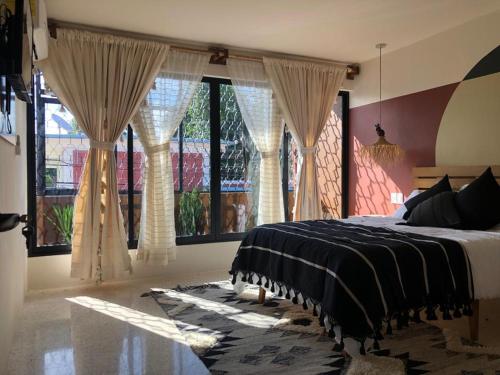a bedroom with a bed and large windows at Casa Crónica in Oaxaca City