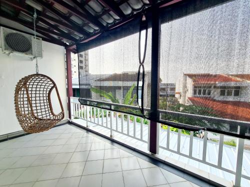 a balcony with a large window with a swing at 527 BeachHouse l 5 bedroom with swimming pool - 3min walk to the beach in Tanjung Bungah
