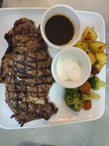 a plate with a steak and a cup of coffee and vegetables at Saipan Beach Hotel in Saipan