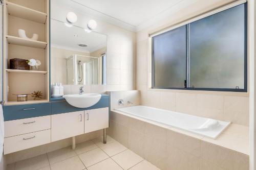 a bathroom with a tub and a sink and a window at Currumbin Beachside Retreat in Gold Coast