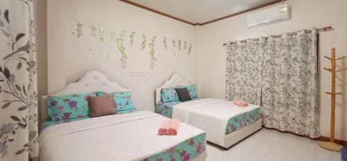2 Betten in einem Zimmer mit rosa Schuhen drauf in der Unterkunft Sweet Floresta Pool Villa in Sattahip