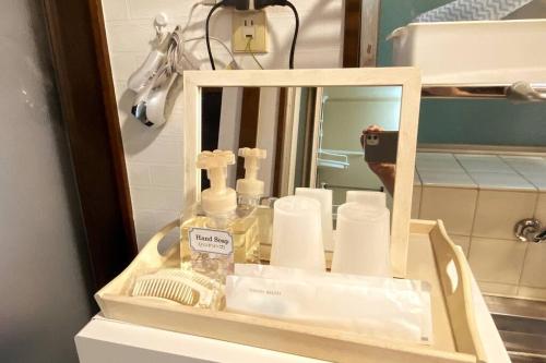 a bathroom vanity with a mirror and toiletries at ラ・ポート空港前107 in Shime