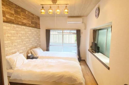 two beds in a room with a brick wall at ラ・ポート空港前107 in Shime