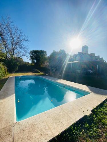 a blue swimming pool with the sun in the sky at Hospedaje Casa Azul in Villa Allende