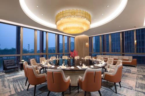 a dining room with a table and chairs and a chandelier at Wanda Jin Xiangjiang Dingzhou in Dingzhou