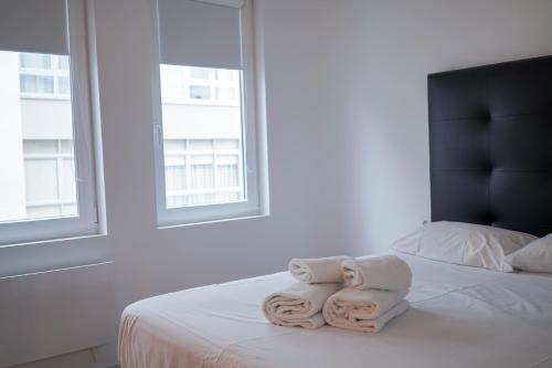 sypialnia z dwoma ręcznikami na łóżku z dwoma oknami w obiekcie Aptartamento Descanso de Hércules - Galitrips w mieście A Coruña