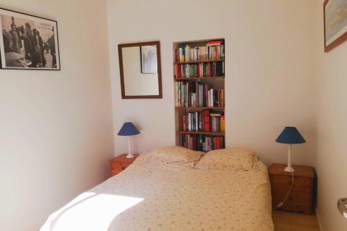 1 dormitorio con 1 cama y estantería con libros en Beautiful house facing the alder wood and beach, en La Baule