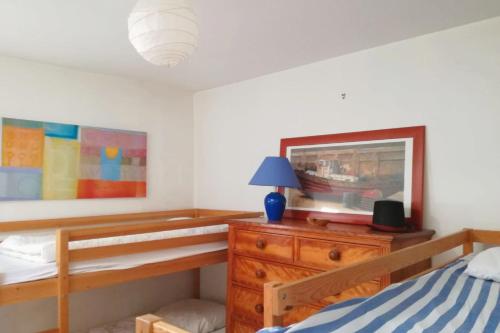 a bedroom with a bed and a dresser with a lamp at Beautiful house facing the alder wood and beach in La Baule