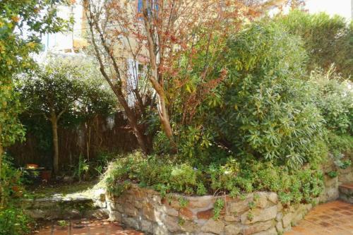 a stone wall with a tree in a garden at Beautiful house facing the alder wood and beach in La Baule