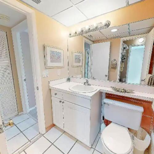 a bathroom with a toilet and a sink and a mirror at Sarasota Pool Apartment in Siesta Key