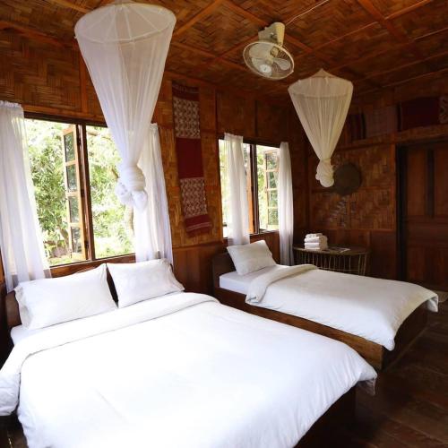 dwa białe łóżka w pokoju z oknami w obiekcie Ning Ning Guesthouse w mieście Ban Ngoy-Nua