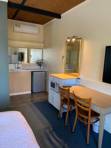 a room with a table and chairs and a kitchen at Temora Motel in Temora