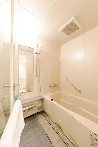 a bathroom with a tub and a mirror at Pangoo Shinagawa in Tokyo